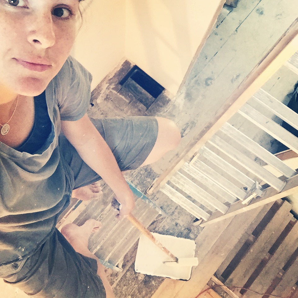 paint on a roller on a pole on a woman on a ladder in a house